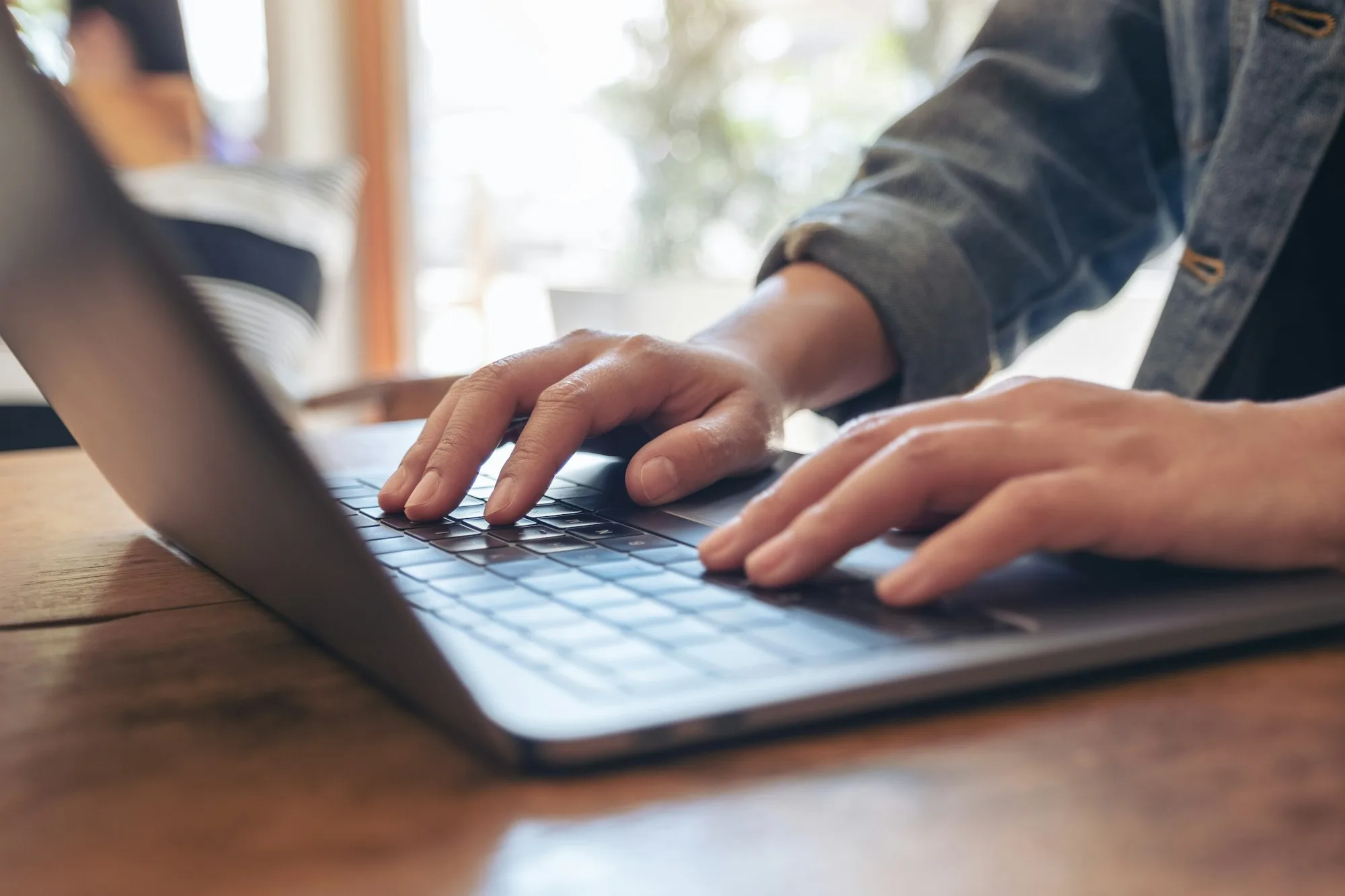 Closeup image of woman’s hands using and typing on laptop keyboard on the table Closeup image of woman's hands using and typing on laptop keyboard on the table